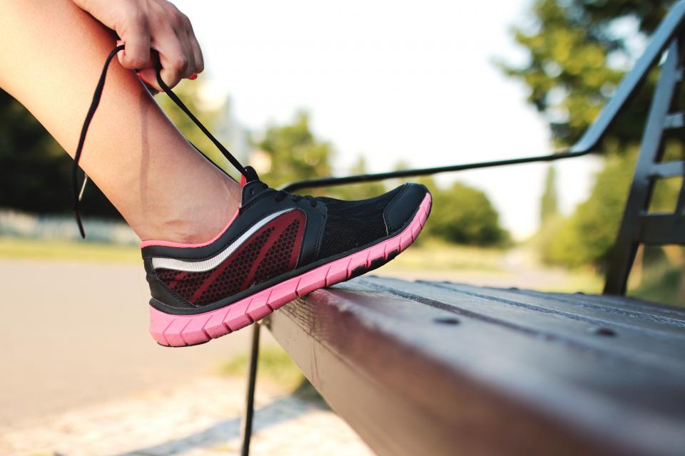 Paio di scarpe da corsa consumate appoggiate sull'asfalto vicino a una panchina
