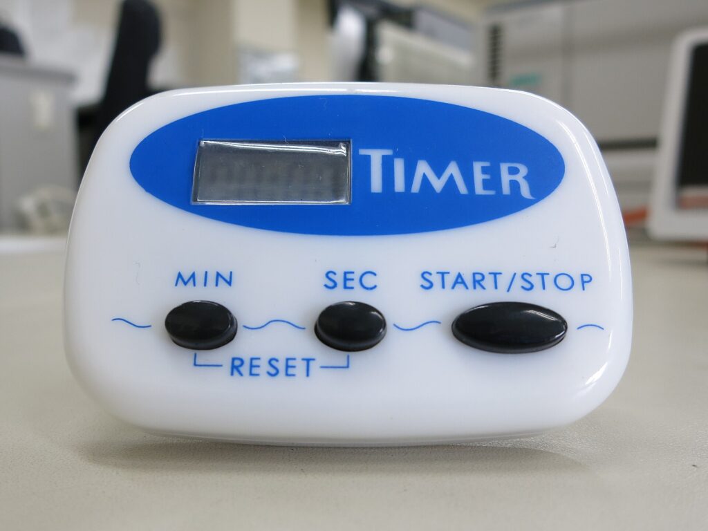 Timer da cucina meccanico bianco fotografato da vicino su un piano neutro