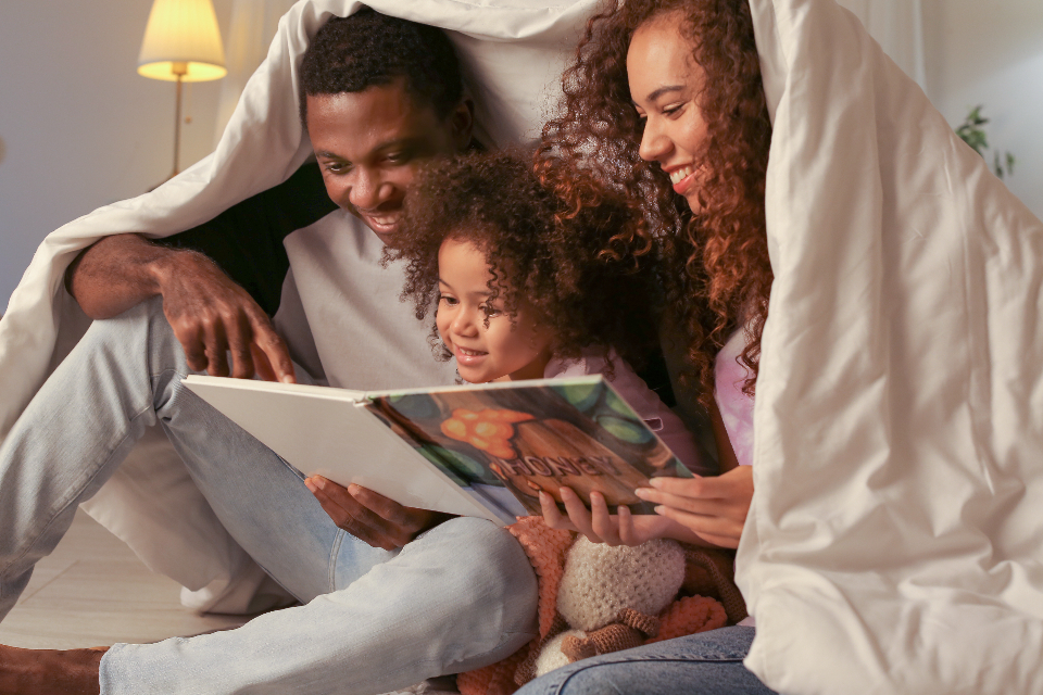 Adulto e bambino seduti vicini mentre leggono insieme un libro illustrato